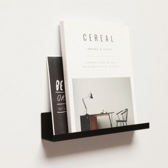 Poliță metalică neagră simplă pentru magnetic, montată pe perete cu o ramă foto pe ea.