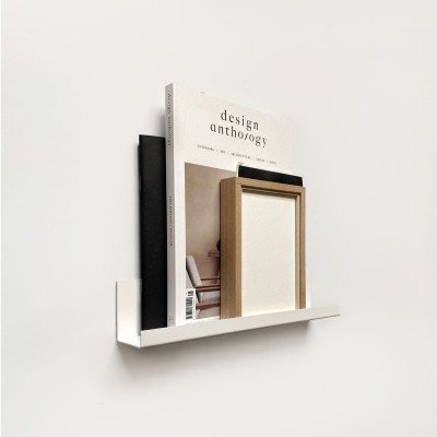 Poliță metalică simplă pentru perete, albă, cu un design minimalist. Pe ea sunt așezate un cadru, o carte și o figurină.