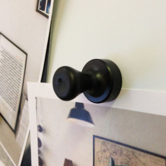 Magneți negri în formă de pion care țin o fotografie