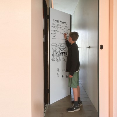 Băiat scriind pe o tablă magnetică albă